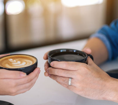 Two people holding coffee cups with a blurred background