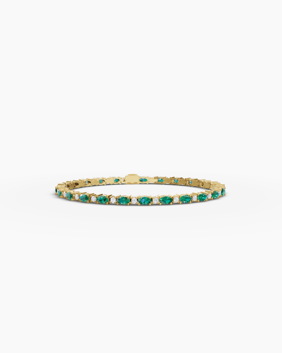 Gold bracelet with green and clear stones on a white background