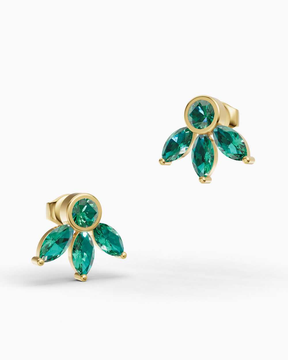 Gold earrings with green gemstones on a white background