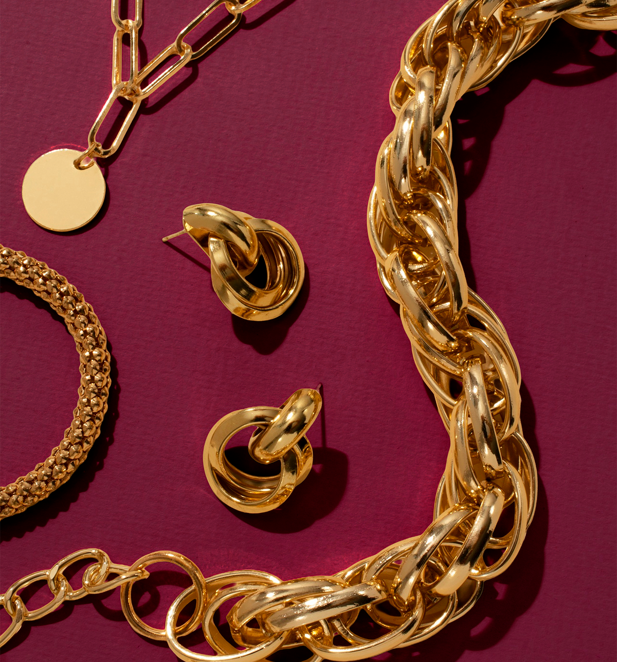 Gold jewelry including a necklace, bracelet, and earrings on a red background