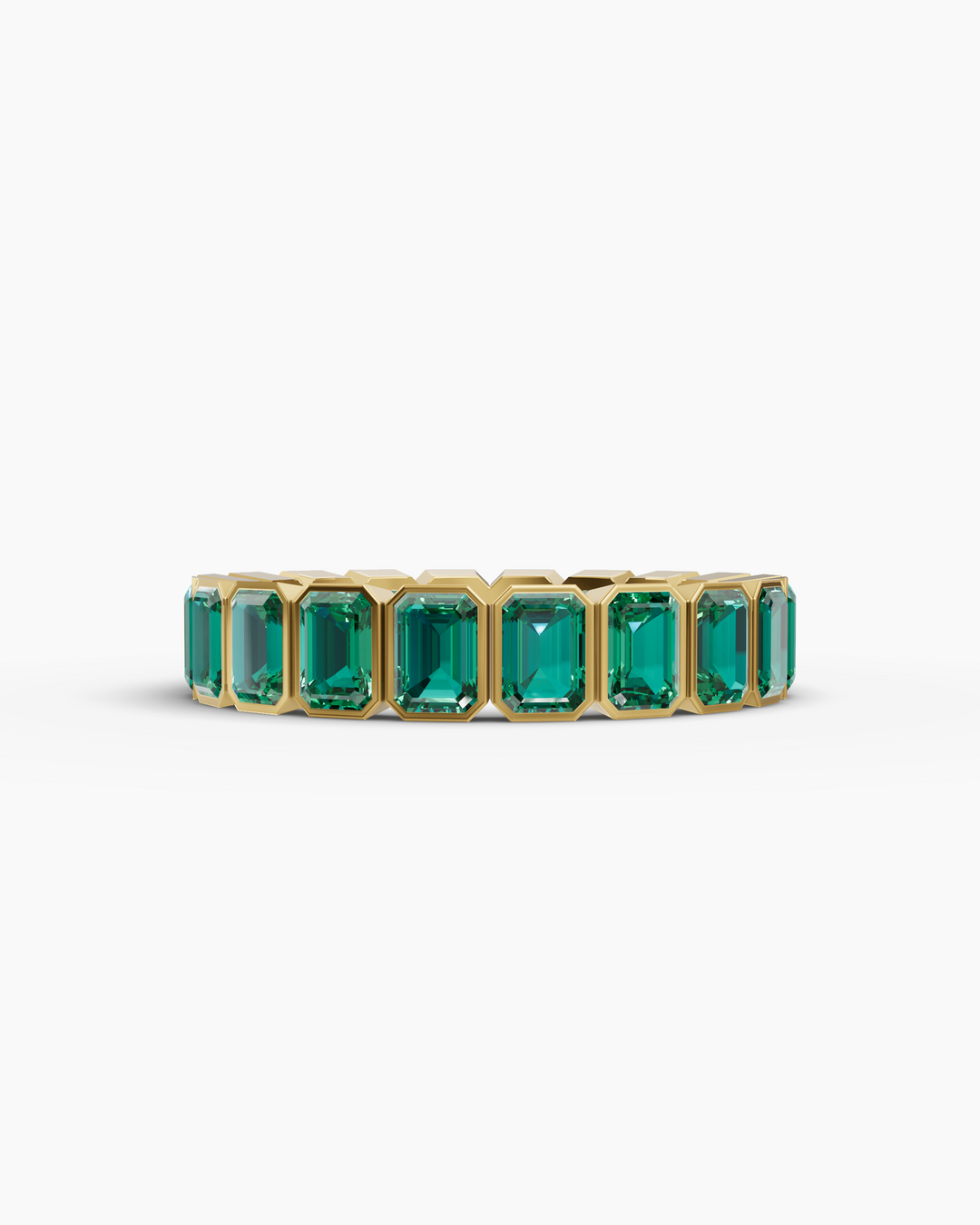 Gold ring with emerald green gemstones on a white background